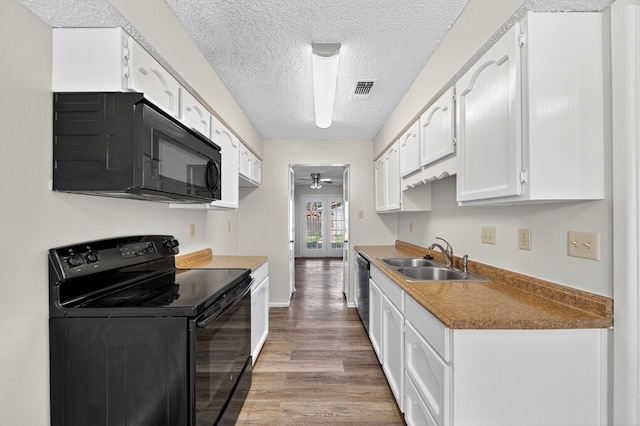 3208 Preston Dr, Midland, TX 79707 - kitchen with black appliances, ceiling fan, light wood-style floors, a textured ceiling, and white cabinetry