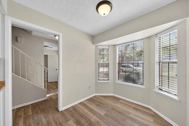 3208 Preston Dr, Midland, TX 79707 - empty room featuring wood finished floors, a textured ceiling, and stairs