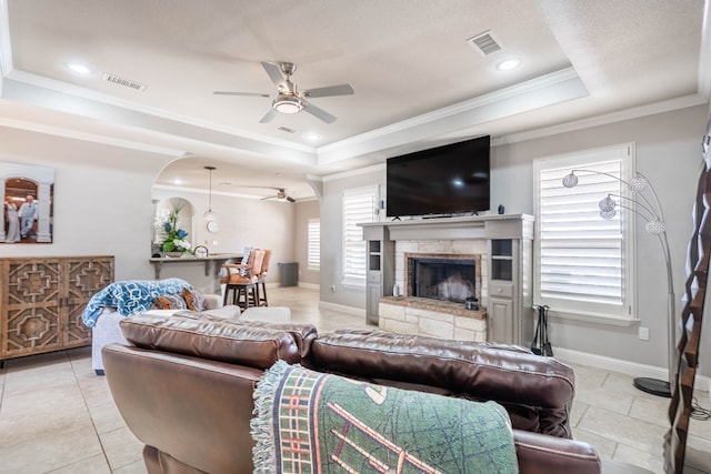 7209 E County Rd 96, Midland, TX 79706 - living room with a ceiling fan, a tray ceiling, a stone fireplace, baseboards, and ornamental molding