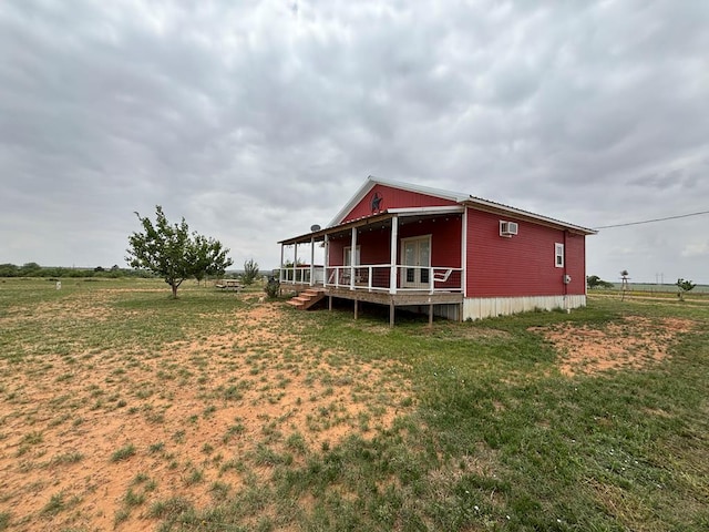 rear view of property featuring a lawn and a wall mounted air conditioner
