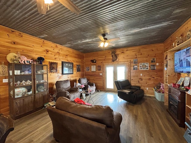 living area with wooden walls, ceiling fan, and wood finished floors