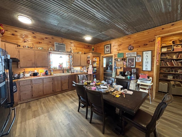 dining space with wood walls, a wall unit AC, and light wood-style flooring