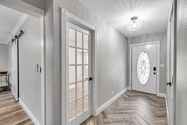 foyer with a barn door, baseboards, and crown molding