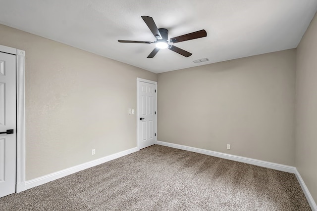 empty room with carpet floors, visible vents, baseboards, and ceiling fan