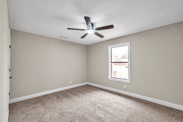 unfurnished room with a textured ceiling, a ceiling fan, visible vents, baseboards, and carpet