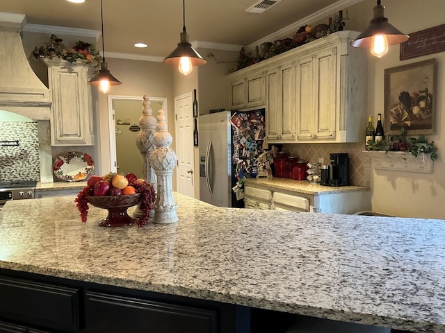 kitchen featuring backsplash, ornamental molding, exhaust hood, pendant lighting, and cream cabinets