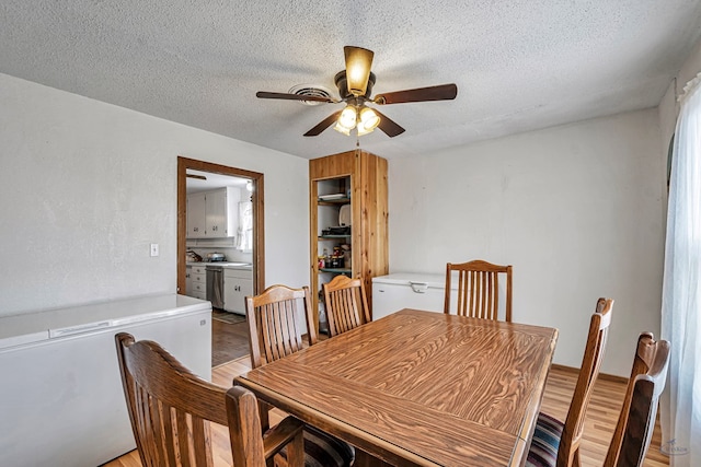 dining area with ceiling fan, light hardwood / wood-style flooring, and a textured ceiling