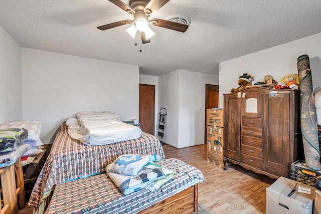 bedroom with ceiling fan, a textured ceiling, and light wood-type flooring