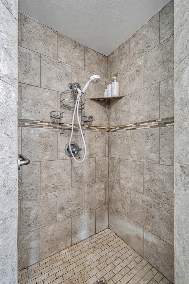 bathroom with a tile shower and a textured ceiling