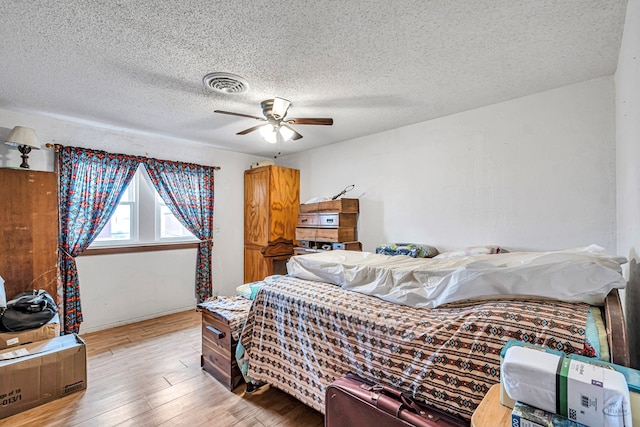 bedroom featuring ceiling fan, a textured ceiling, and light hardwood / wood-style flooring