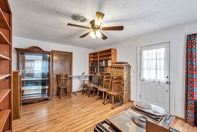 interior space featuring a textured ceiling, ceiling fan, and light wood-type flooring