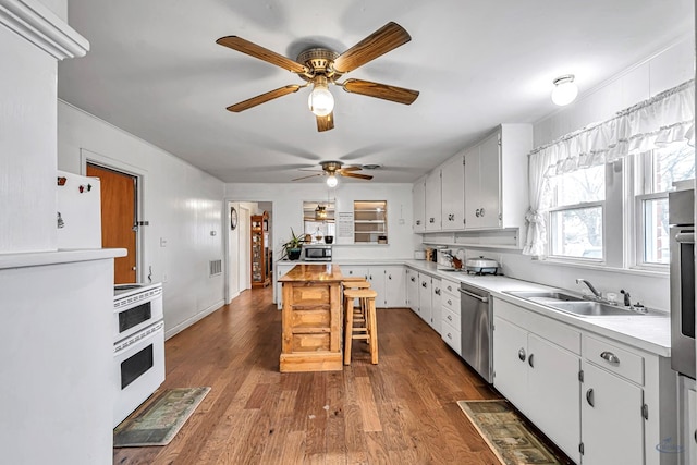 kitchen with dark hardwood / wood-style floors, sink, white cabinets, a kitchen bar, and stainless steel appliances