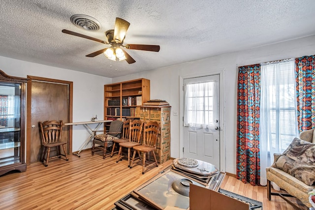 interior space featuring ceiling fan, a textured ceiling, and light hardwood / wood-style floors