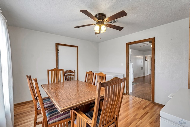 dining space with ceiling fan, a textured ceiling, and light wood-type flooring