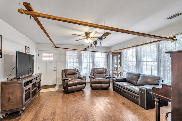 living room featuring beam ceiling, wood-type flooring, and ceiling fan