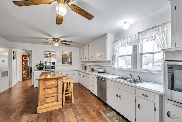 kitchen with dark wood-type flooring, appliances with stainless steel finishes, sink, and white cabinets