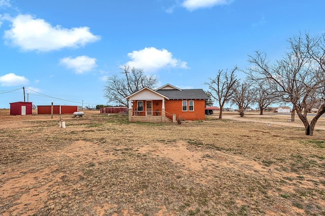 rear view of property featuring a yard, covered porch, and a rural view