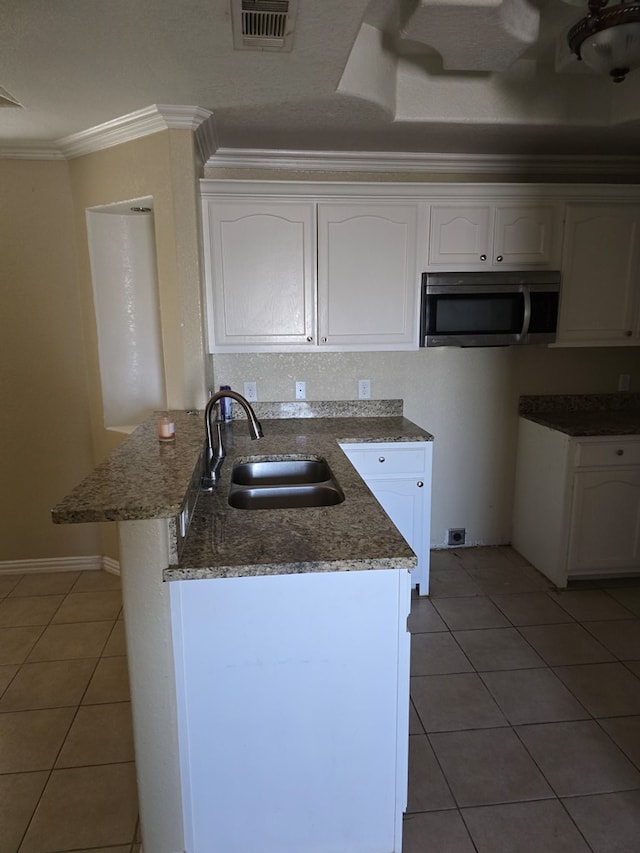 kitchen featuring tile patterned flooring, white cabinetry, dark stone countertops, sink, and crown molding