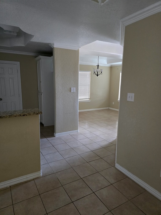 tiled empty room featuring an inviting chandelier and ornamental molding