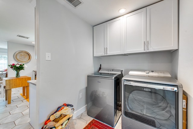 washroom with washer and dryer, light tile patterned floors, and cabinets