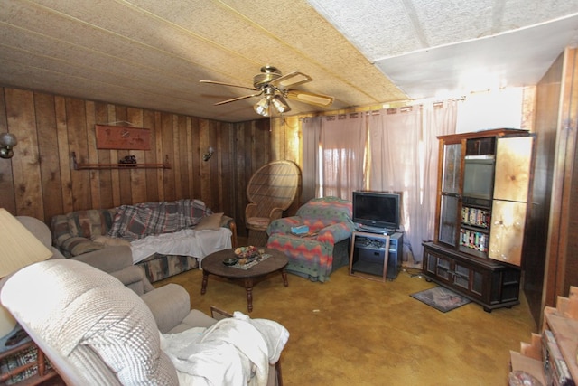 living area with a ceiling fan and wood walls