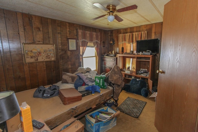 bedroom featuring ceiling fan, wood walls, and carpet flooring