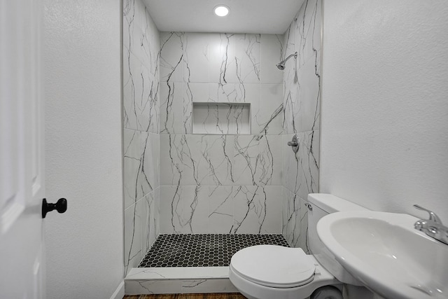 bathroom with sink, toilet, and tiled shower