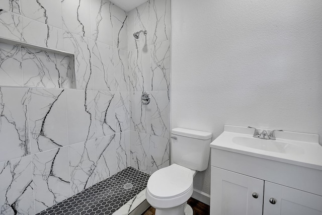 bathroom featuring vanity, toilet, and a tile shower