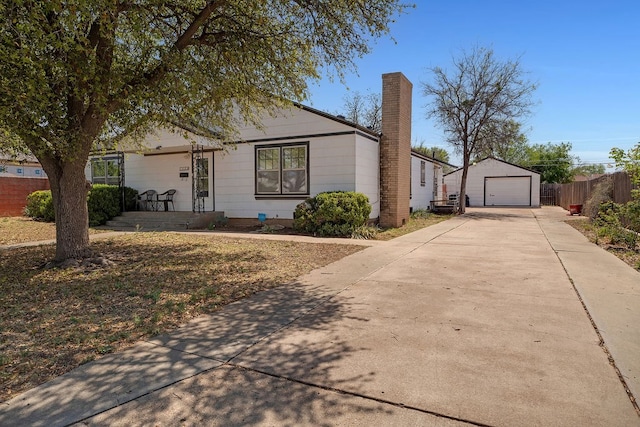 ranch-style house with fence, a garage, an outbuilding, a chimney, and concrete driveway