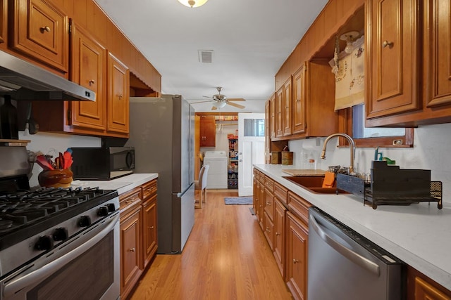 kitchen featuring visible vents, washer / dryer, light countertops, a sink, and stainless steel appliances