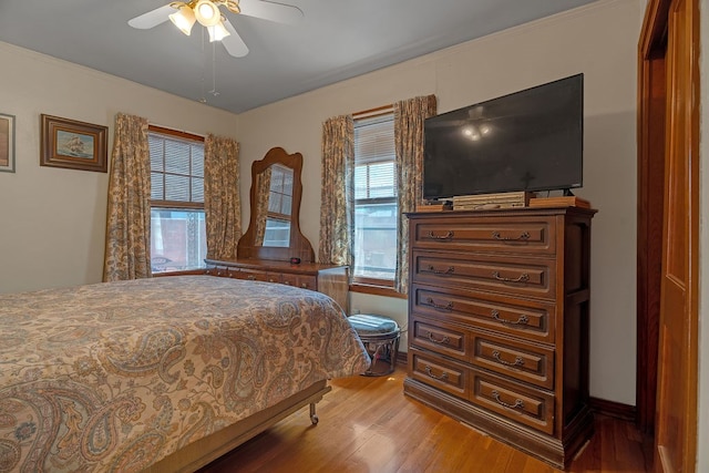 bedroom featuring baseboards, multiple windows, a ceiling fan, and light wood-type flooring