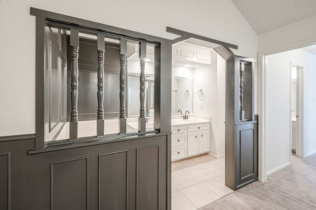 bathroom with a textured ceiling, tile patterned flooring, vanity, baseboards, and vaulted ceiling