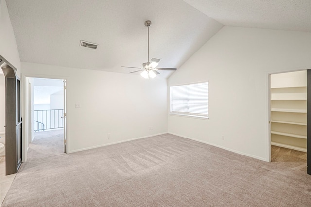 empty room featuring lofted ceiling, a textured ceiling, light colored carpet, visible vents, and baseboards