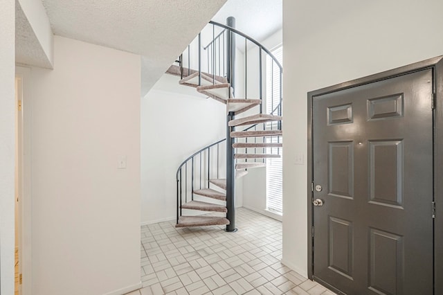 entrance foyer featuring brick floor, a textured ceiling, baseboards, and stairs