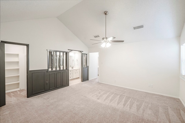 empty room featuring light carpet, ceiling fan, built in shelves, and visible vents