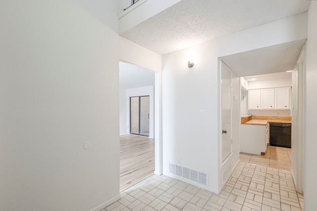 corridor featuring baseboards, visible vents, and a textured ceiling