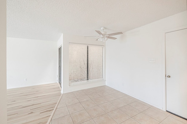 unfurnished room with ceiling fan, a textured ceiling, and baseboards