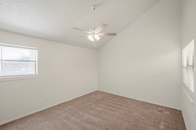 empty room featuring a ceiling fan, light carpet, vaulted ceiling, a textured ceiling, and baseboards