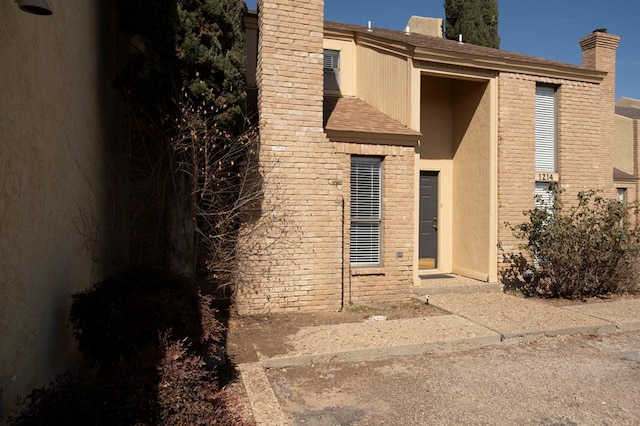 exterior space with roof with shingles, a chimney, and stucco siding