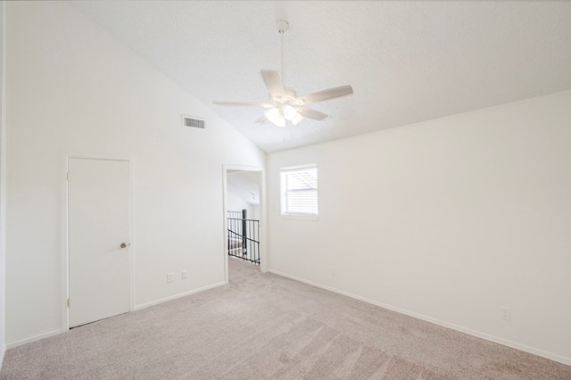 unfurnished room with light carpet, visible vents, a ceiling fan, lofted ceiling, and a textured ceiling