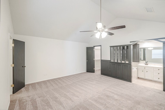 unfurnished bedroom featuring lofted ceiling, light colored carpet, a sink, and a spacious closet