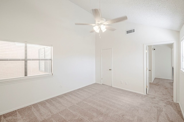 spare room featuring lofted ceiling, ceiling fan, a textured ceiling, light colored carpet, and visible vents