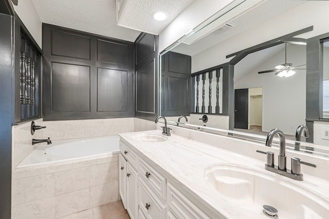 bathroom featuring a sink, a textured ceiling, a bath, and double vanity