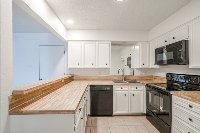 kitchen with light tile patterned floors, black appliances, a sink, and white cabinetry