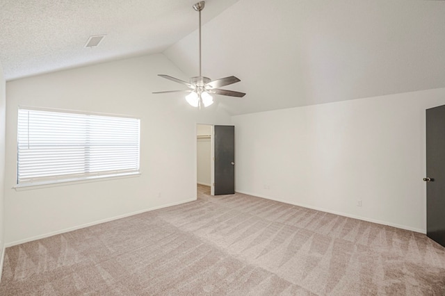 unfurnished room with light carpet, baseboards, a ceiling fan, vaulted ceiling, and a textured ceiling