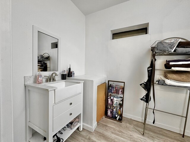 bar featuring white cabinets, light hardwood / wood-style floors, and sink