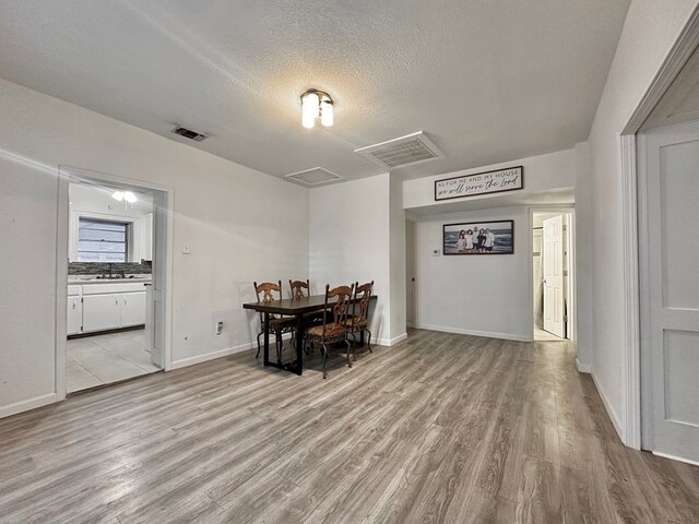 dining room featuring light wood-type flooring and a textured ceiling