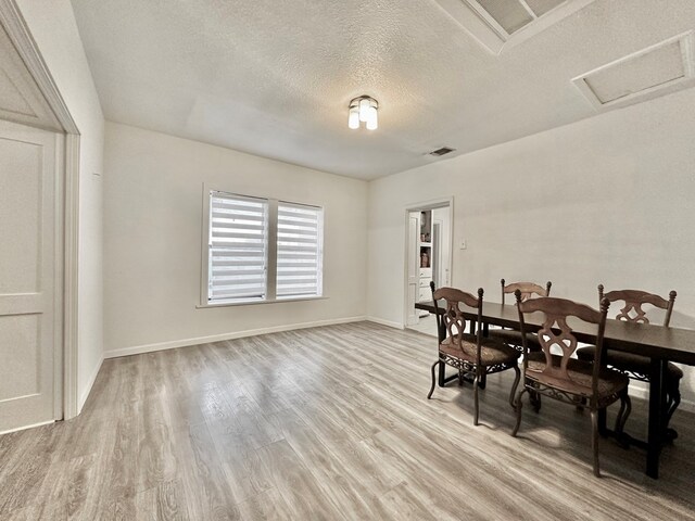 dining room with a textured ceiling and light hardwood / wood-style flooring