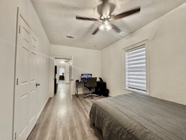 bedroom featuring ceiling fan, light hardwood / wood-style floors, and a textured ceiling