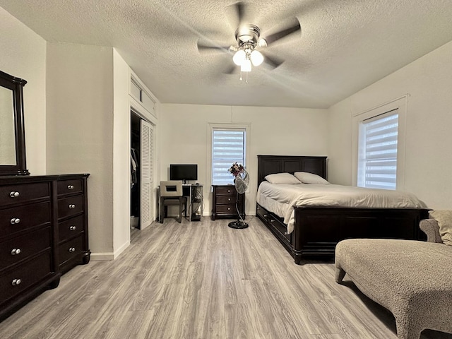 bedroom featuring ceiling fan, a closet, light hardwood / wood-style floors, and a textured ceiling